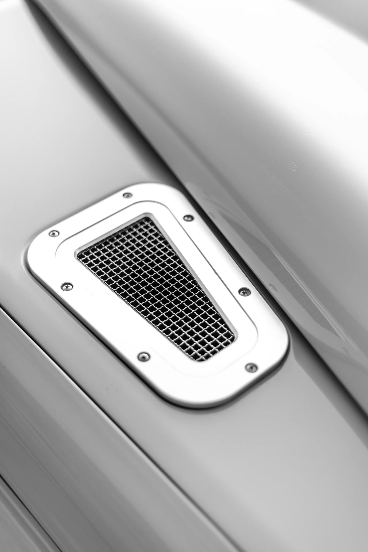 Black-and-white close-up of a Defender wing vent with a polished metal surround