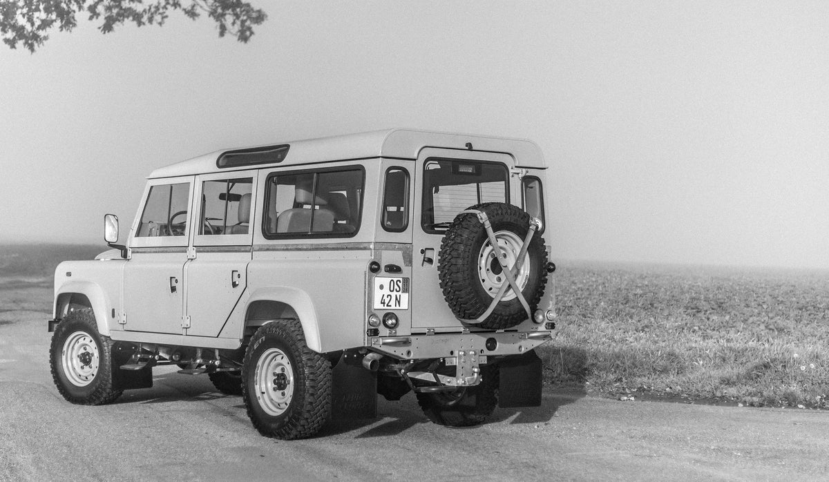 Black-and-white rear three-quarter view of the Miami Blue Defender 110 in a field