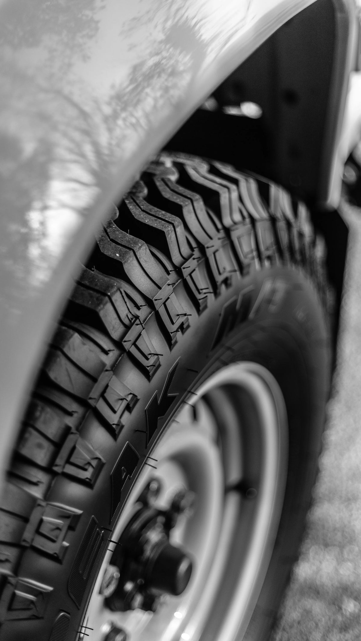 Black-and-white close-up of a Defender wheel, tyre and wheel arch