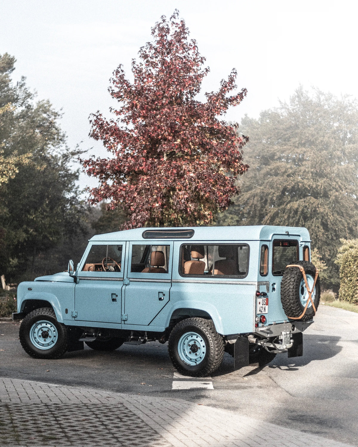 Rear three-quarter view of the Miami Blue Defender 110 with its hardtop and terracotta leather interior