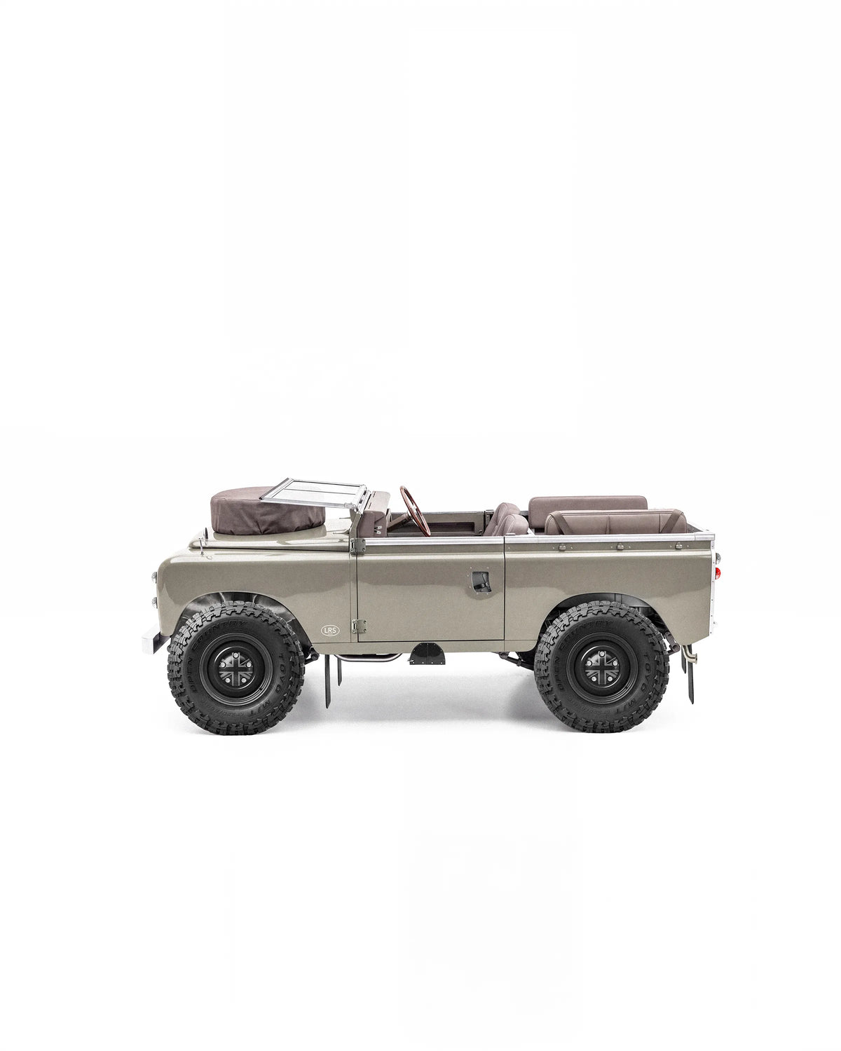Side profile of an open-top Series Land Rover with a folded windscreen and brown leather seats